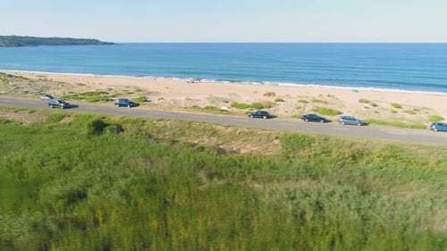 Drone Follows Speeding Black SUV on Sea Road with Sand Beach and Crashing Waves in the Back