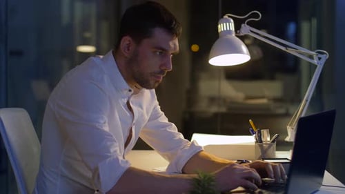 Businessman with Laptop Working at Night Office