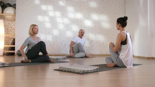 Couple caucasien d'âge moyen faisant du yoga avec un professeur en studio
