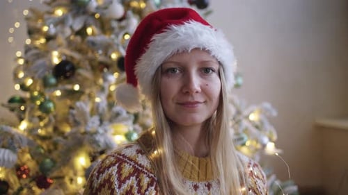 Smiling Woman Wearing Santa Hat by Christmas Tree