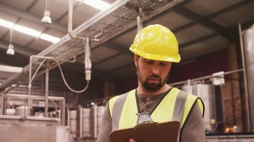 Worker examining while writing on clipboard