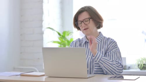 Woman Typing and Rubbing Stiff Neck in Bright Office