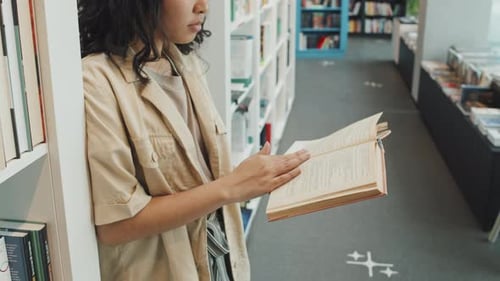 Asiatischer Student liest Papierbuch in der Bibliothek
