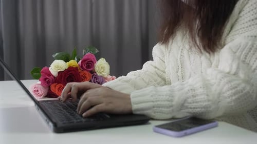 Woman Typing on Laptop with Colorful Roses