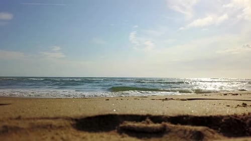 Unter blauem Himmel rollen die Wellen am Strand