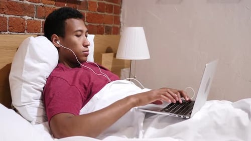 Young Adult Using Laptop in Bed