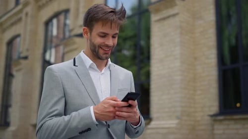 Businessman Surfing Internet Outdoors. Man Messaging By Mobile Phone on Street.