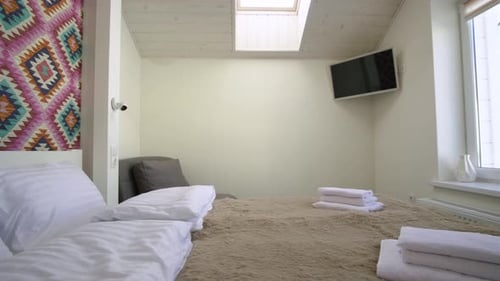 Interior de una espaciosa habitación de hotel en el ático con ropa de cama limpia sobre una cama doble grande.
acogedor