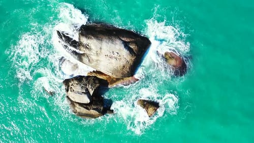 Beautiful limestone cliffs splashed by turquoise ocean foaming water on shore of tropical island in