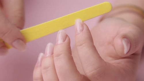 Hands Filing Long Nails on Pink Background
