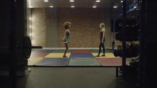 Adult woman exercising in gym with personal trainer