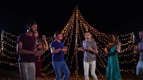 Young Friends with Glasses of Alcohol in Hand Actively Dance at a Beach Disco