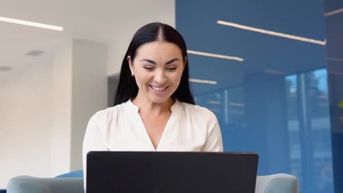 Excited Woman Celebrates Success Using Laptop at Work