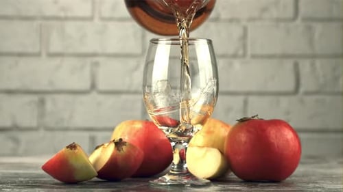 Pouring Apple Juice into Glass with Apples