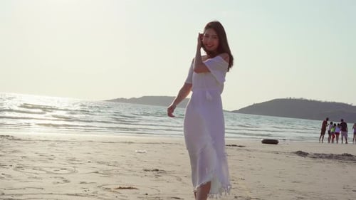 Asian woman walking on beach near sea when sunset in evening.
