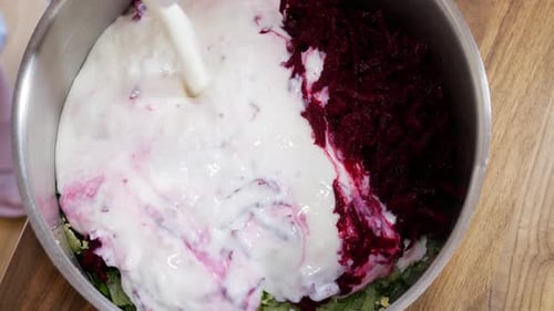 Pouring kefir into bowl with ingredients for cold beetroot soup, static view