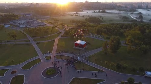 Students Launch Colourful Balloons in Sunrise Lights in the City Park Aerial