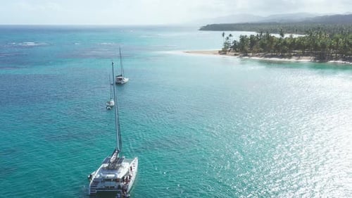 Luxurious boats anchored at Playa Punta Popy, Las Terrenas in Dominican Republic. Aerial backward