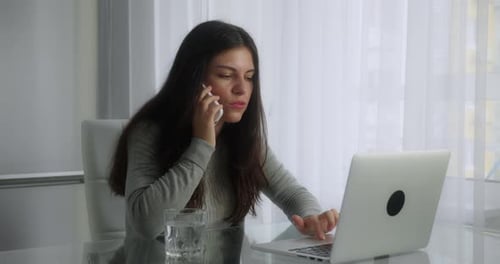 Woman Working on Laptop While Talking on Phone