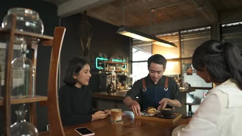 Garçom de homem asiático 4K servindo café com leite e padaria para cliente mulher na mesa do café
