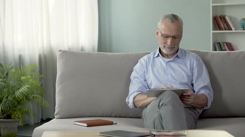Senior Man Using Tablet on Couch at Home
