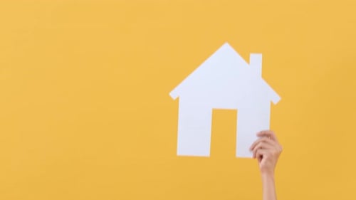 Paper House Raised in Front of Yellow Background
