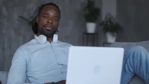 Man Relaxes on Couch with Laptop and Headphones
