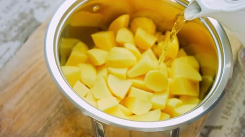 O cozinheiro derrama água de uma tigela sobre as batatas cozidas
