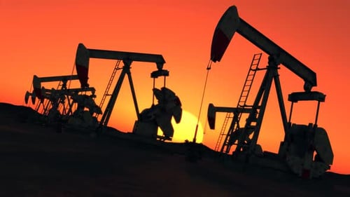 Silhouette of oil pumps pumping the crude oil into pipelines at the desert.