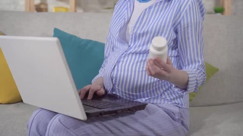 Pregnant Woman Using Laptop with Medicine