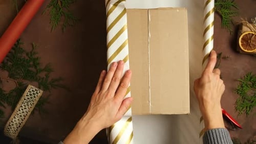 Hands Wrapping Christmas Gift on Table
