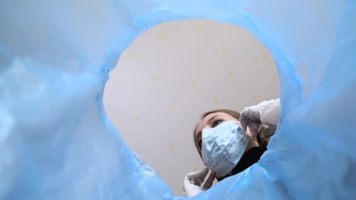Woman Discards Face Mask into Blue Trash Bin