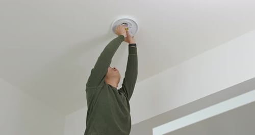 Man Installing Ceiling Light Fixture in Home