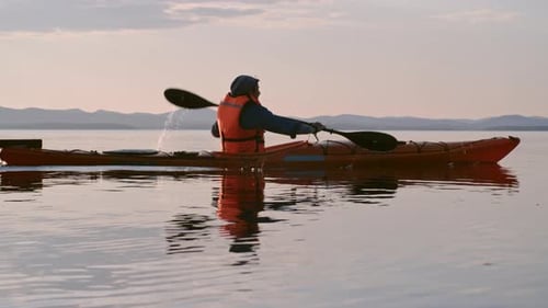 Kayaker Paddling on Calm Lake at Sunrise