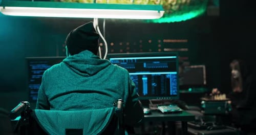 Un homme en fauteuil roulant Un pirate informatique à capuchon travaille sur un ordinateur avec des données affichées