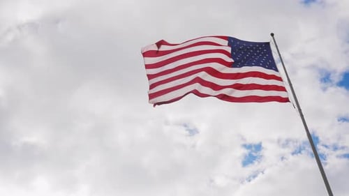 American Flag Waving Against Partly Cloudy Sky