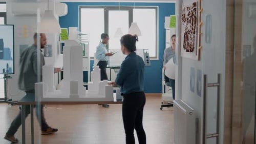 Group of Colleagues Meeting to Analyze Building Model and Maquette to Plan Blueprints