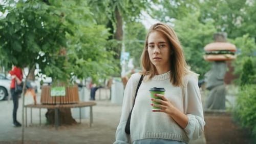 Joyful Girl Drinks Tea on the Street in Rainy Weather and Speaks on the Phone