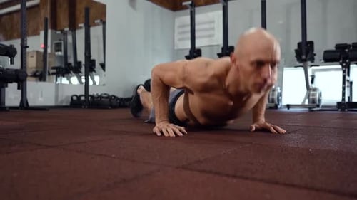Homme faisant burpee dans la salle de gym
