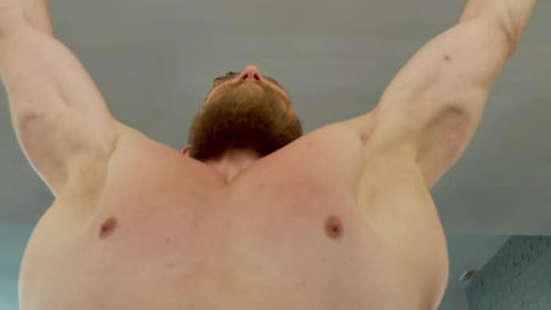 Handsome Athlete Doing Pull Ups in an Indoor Gym