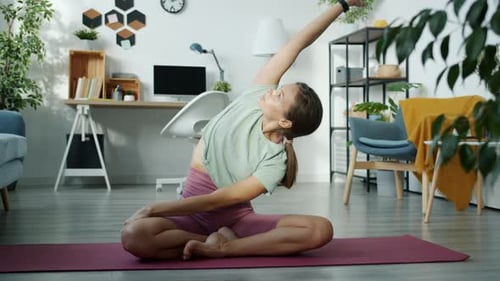 Adult Woman Practices Yoga Stretching at Home