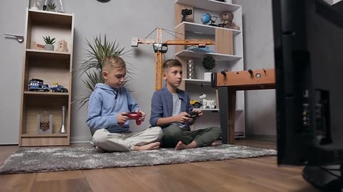 Teenager-Brüder sitzen auf dem Teppich und treten mit Gamepads im Videospiel an