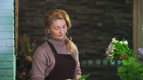 Woman Florist Cleanse Fir Branch From the Pine Needles To Prepare the Bouquet. Look at the Camera