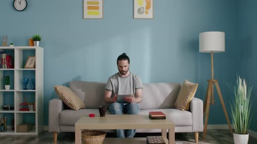 Young Adult Using Tablet on Couch at Home