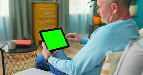 Adult Old Man at Home Uses Green Mockup Screen Tablet
