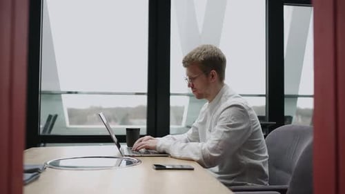 Adult Man is Working Alone in Modern Office Using Laptop with Wireless Internet Connection for