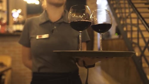 Waitress Carries Red Wine To Guests Sitting in Restaurant
