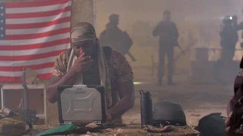 Man in Camouflage Using Laptop and Radio