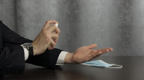Man in Suit Disinfecting Hands with Hand Sanitizer