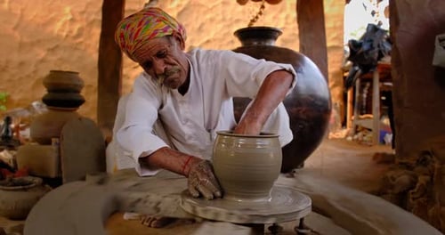 Potier indien au travail : lancer le volant du potier et façonner un récipient en céramique et des articles en argile : pot